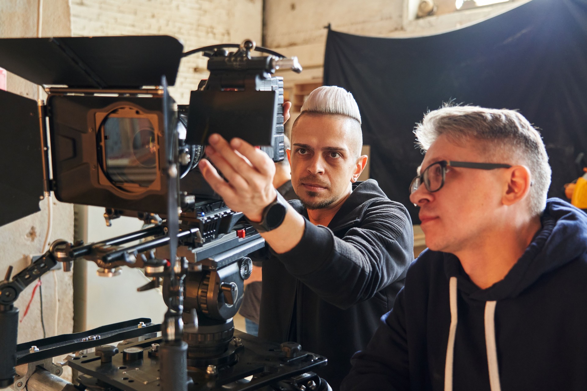 professional videographer and film director stand behind a professional movie camera on set and look at the camera monitor